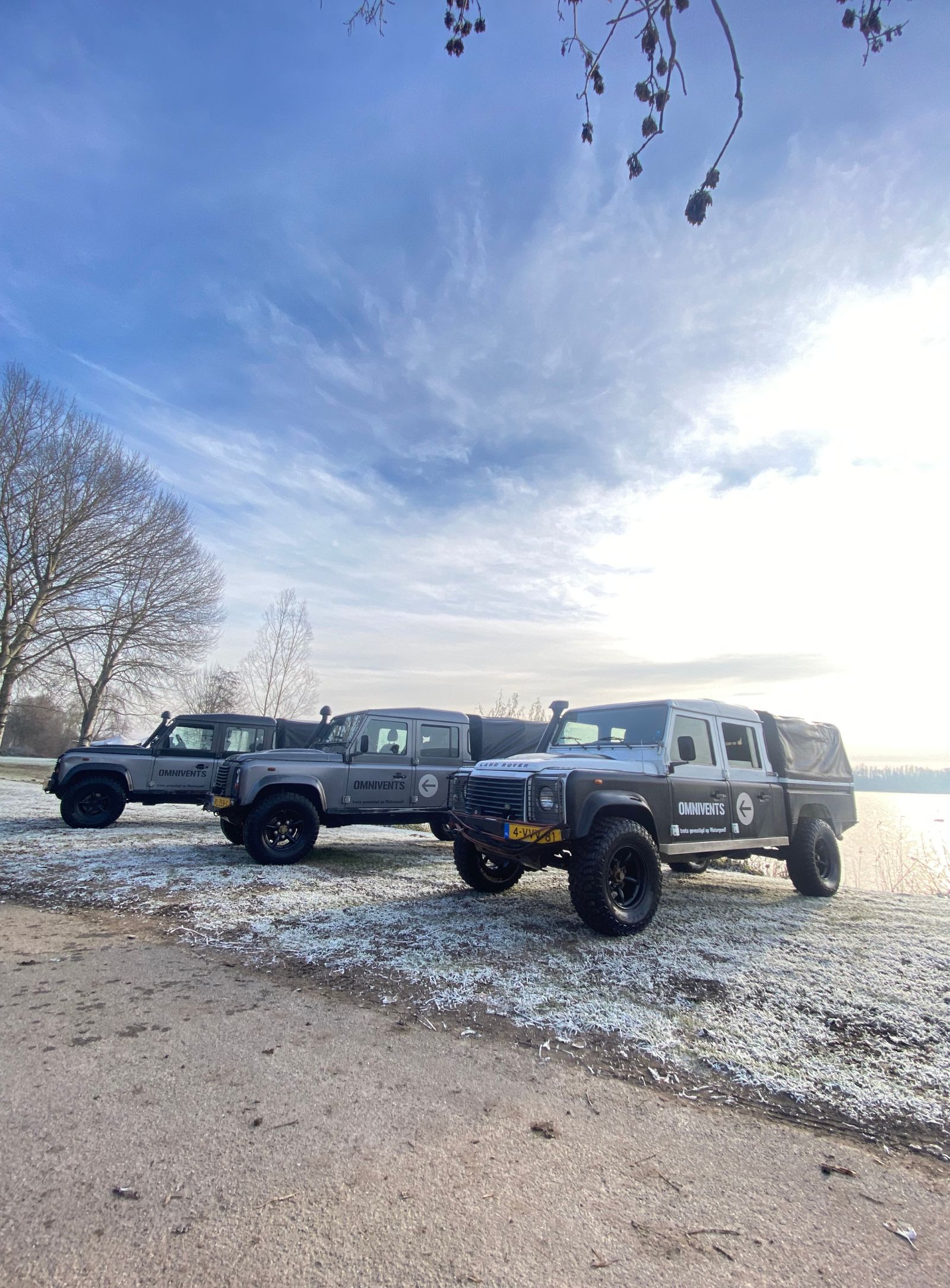 Land Rovers op een rij tegen een winter achtergrond op bevroren gras met zon