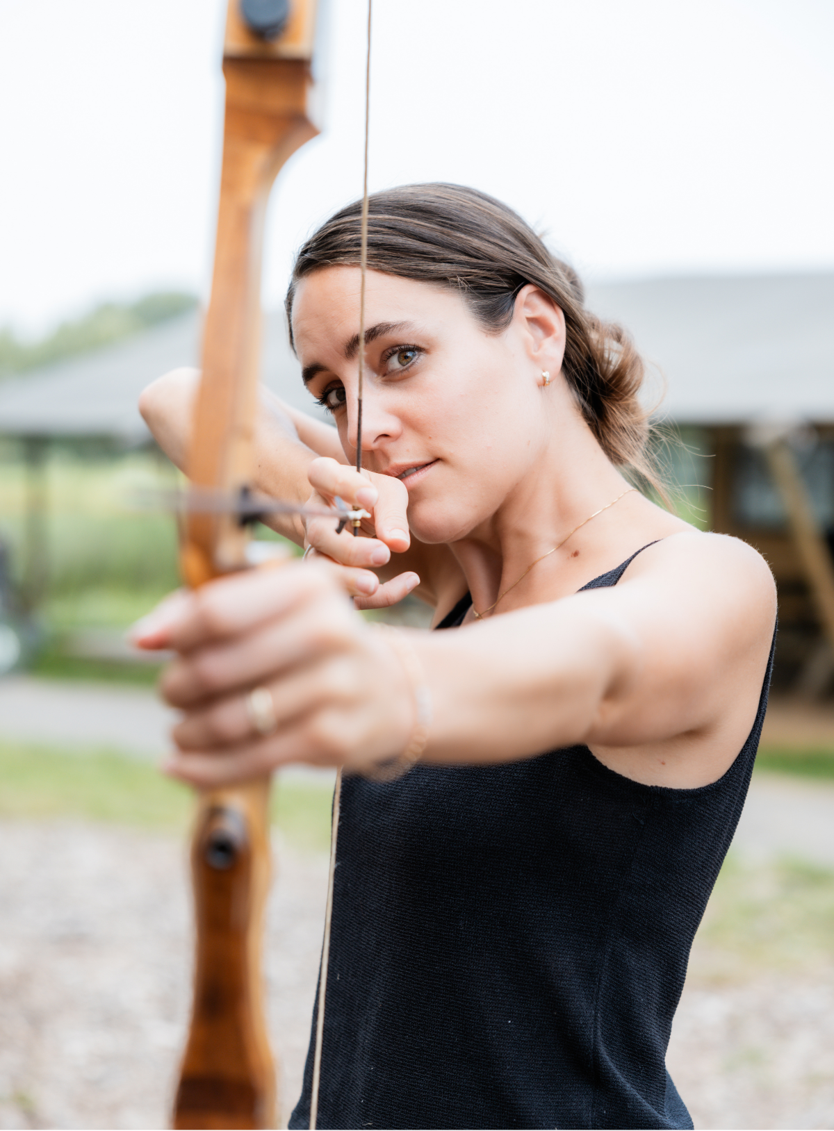 Vrouw knijpt haar oog dicht tijdens het richten met een handboog